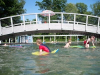 Spielende Kinder im Naturschwimmbad Stamsried. Wasserspielgerte sind vor Ort vorhanden