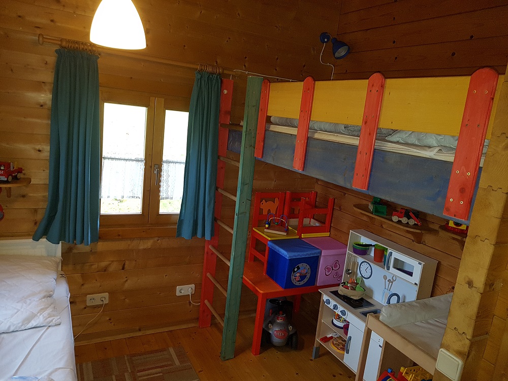 Blick in das 2. Schlafzimmer das auch als Kinderzimmer dient. Ausziehbares Doppelbett, Spielecke, Wickeltisch, Kindersitzecke, Spielzeug und Hochbett ber der Spielecke.